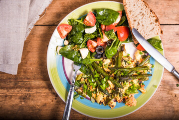 American lunch - scrambled eggs with asparagus on a plate with tomato, spinach and cheese salad. Healthy eating