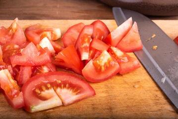 Knife and tomatoes cut for salad on a cutting kitchen board close-up, macro, no people