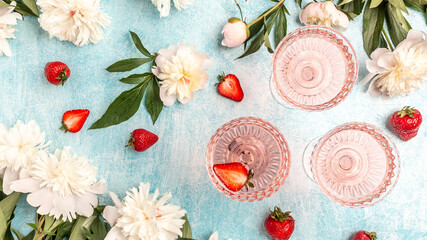 Rose wine in glasses with Peony Flowers and sweet fresh strawberries on blue background, Summer...