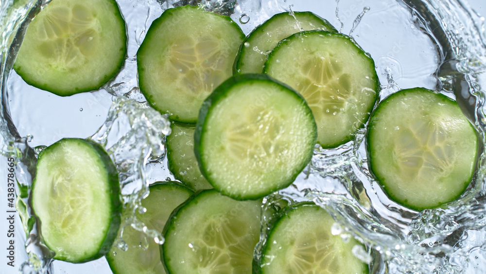 Fototapete sliced cucumber splashing water isolated on white background, macro shot.