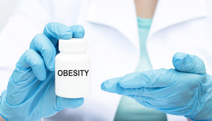 Fototapeta premium Close-up of a hands doctor in gloves with a white medicine jar on which the text OBESITY