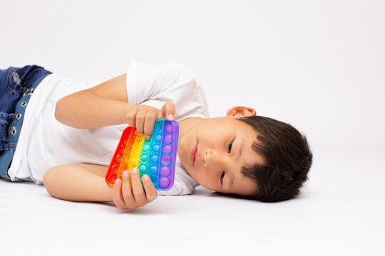 Child plays with sensory fidget toy Pop-it. Instrument for fine motoric skils, tool to start counting, learn primary arithmetic operations. A sedative for finger stimulation, relaxation.