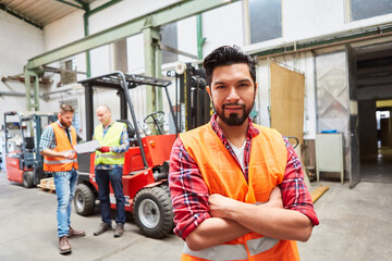 Warehouse worker with crossed arms in front of forklift truck - obrazy, fototapety, plakaty