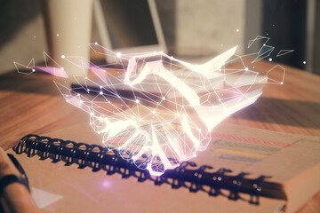 Double exposure of handshake flying drawings and desk with open notebook background. Concept of partnership