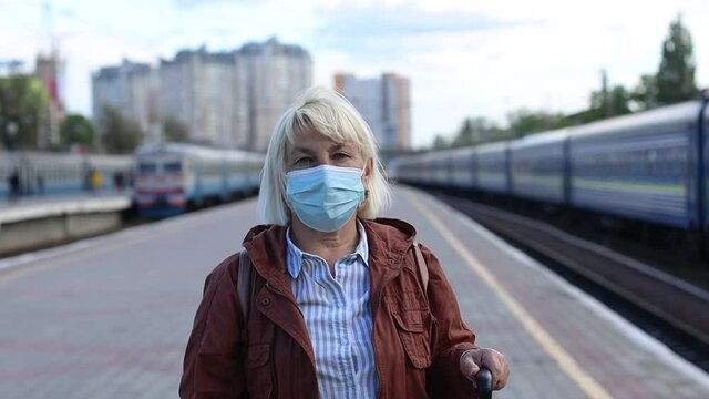 Portrait of senior woman wearing protective face mask outdoors at the train station