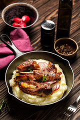 Oven-roasted pork ribs with mashed potatoes on a wood table. Top view, vertical image.