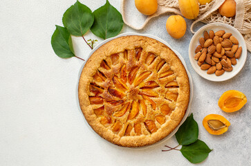 Homemade apricot and almonds pie on light table. Top view. Copy space.