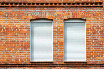 Fragment of a brick wall of a building with two windows.