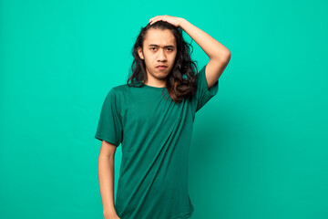 young man with long hair  with a serious face isolated on blue background