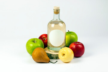 Homemade natural alcohol production concept. Transparent glass bottle on cross cut wooden logs, pear and various color apples isolated on white background. Part of set.