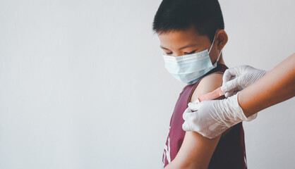 Asian boy showing his arm after getting covid-19 vaccine.