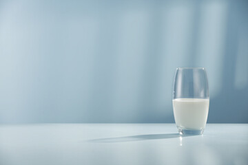 Glass of milk on desk and wall with shadow 