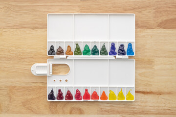 Colorful watercolor paints set in watercolour palette on wood. Multicolored aquarelle paints in paint box.
