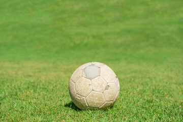 Plakat Old soccer ball on green grass of soccer field.