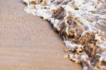 Sandy beach and sea foam macro with narrow focus background. Texture of a splash of bubbles and grains of sand.