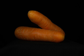 two orange carrots isolated on a black background