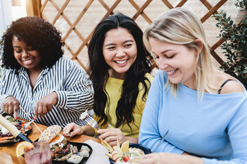 Young multiracial people having breakfast outdoor at patio restaurant - Focus on asian girl face