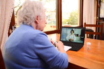 elderly senior woman, having a remote medical consultation with her female doctor over internet and laptop computer telemedecine diagnostic.