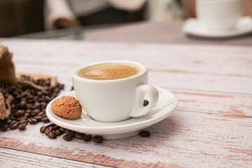 Fototapeta premium Cup of coffee with beans on a light wooden table.