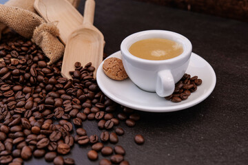 Coffee cup with coffee beans in background on dark background