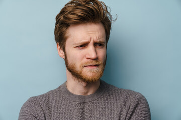 White ginger man with beard frowning and looking aside
