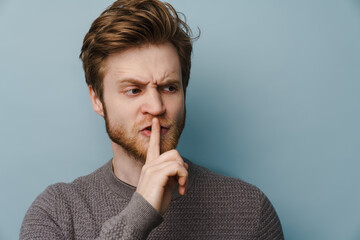 White ginger man with beard showing silence gesture at camera