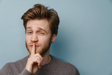 White ginger man with beard showing silence gesture at camera