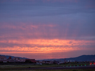 美しい夕焼けを背景に離陸する飛行機のイメージ