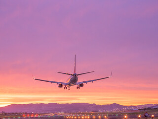 Naklejka na ściany i meble 美しい夕焼けを背景に着陸する飛行機のイメージ