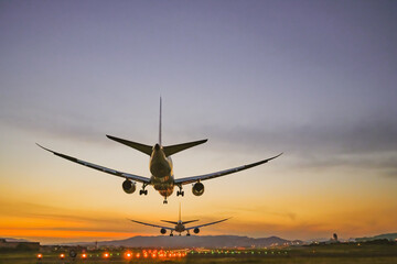 Fototapeta na wymiar 夕陽を背景に着陸する飛行機のイメージ