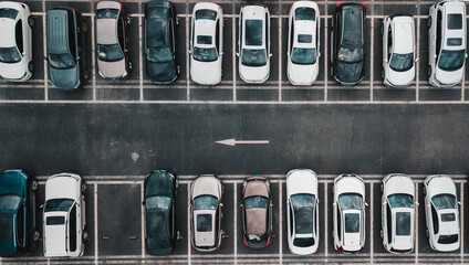 Top down aerial view on payed parking lot with parked cars and one way direction road....