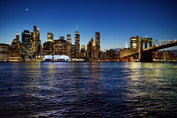 Fototapeta na wymiar Skyscrapers of Manhattan and Brooklyn bridge at dusk. Famous bridge. Postcard view of New York. United States of America landmarks.