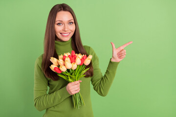 Photo portrait young girl keeping tulips bunch smiling pointing empty space isolated pastel green color background