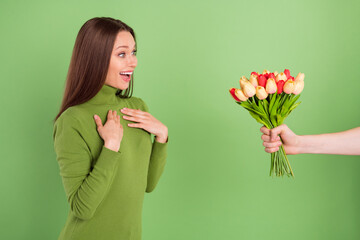 Photo of amazed young positive lady receive flowers hands wow smile isolated on green color...