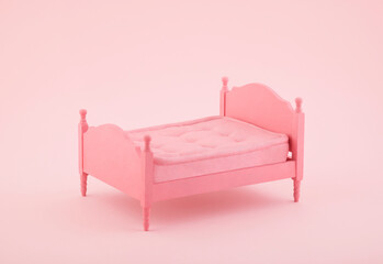 Pink wooden bed miniature on pink background