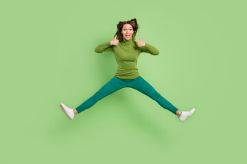 Fototapeta na wymiar Full size photo of charming young happy lady jump up amazed make thumbs up isolated on green color background