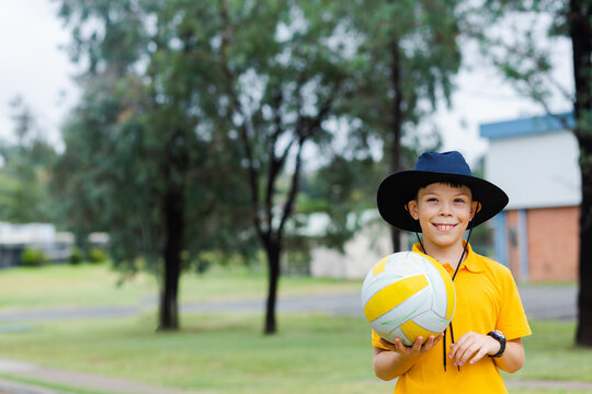 Happy Aussie school boy holding ball to play sports at school