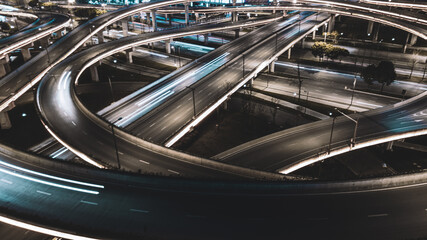 Night long exposure illumination of elevated multilevel traffic junction. Modern development of backlighted roads and current new infrastructure in China, Chengdu. Aerial drone point of view.