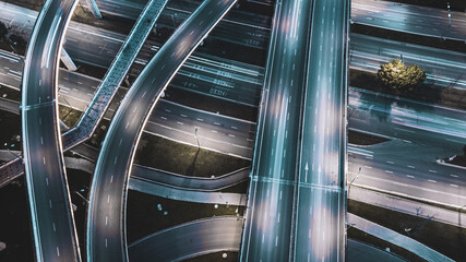 Night long exposure illumination of elevated multilevel traffic junction. Modern development of backlighted roads and current new infrastructure in China, Chengdu. Aerial drone point of view.