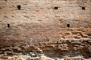 Ruins of an ancient castle. Destroyed brick walls with loopholes. History of ancient architecture. Brick old background