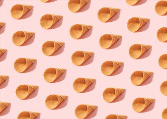 Minimal summer pattern made of empty ice cream cones on sunny pink background.