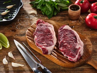 Two juicy raw meat steaks on a wooden cutting board. Beefsteak on kitchen preparation table