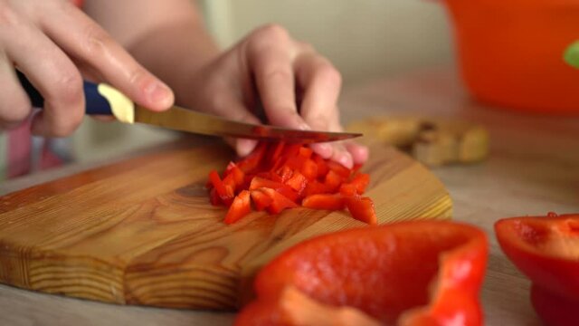 Chopped red Bell Pepper. Girl is cooking food. Cut papper on board. Vegan healthy food. Fresh vegetables.