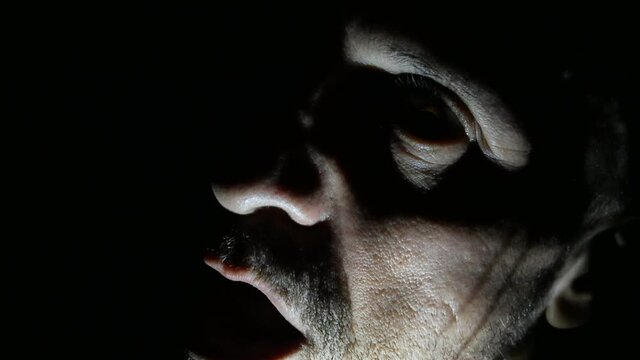 Time lapse of ugly scary devil man in half-light with chiaroscuro, scary and mysterious man screaming while opening his mouth, horror movie and macabre atmosphere