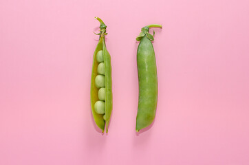 Green peas on a pink background. View from above. Pop art design, creative concept of summer food. Green vegetables, diet, vegetarian. Minimalistic flat style