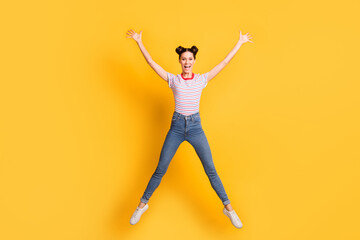 Fototapeta na wymiar Photo of adorable shiny young woman wear striped t-shirt jumping high isolated yellow color background