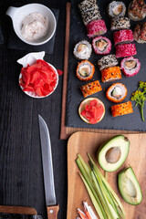 sushi cooking set with rice and ingredients served at black dish at black table. flat lay