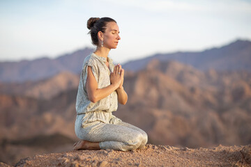 Naklejka na ściany i meble Woman practicing yoga in the mountains in the desert