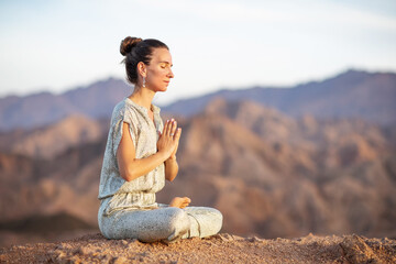 Naklejka na ściany i meble Woman practicing yoga in the mountains in the desert