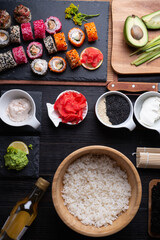 sushi cooking set with rice and ingredients served at black dish at black table. flat lay